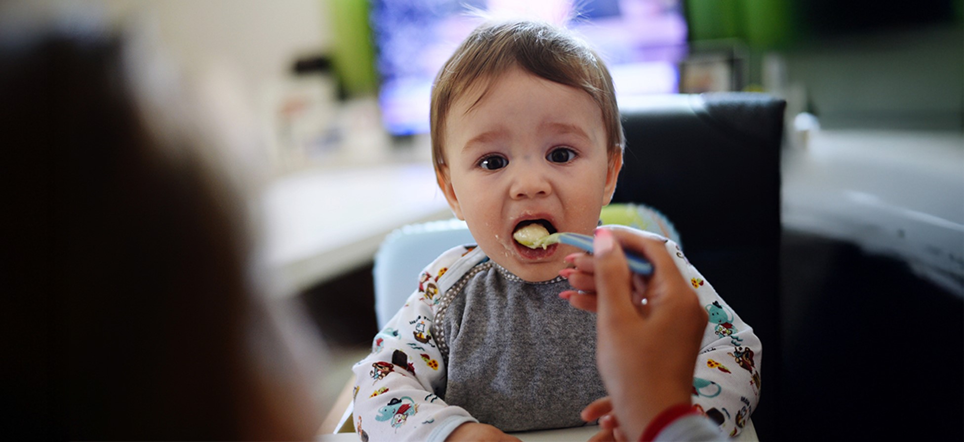 Parent feeding baby with spoon during recovery from vomiting at Rainbow Children’s Hospital