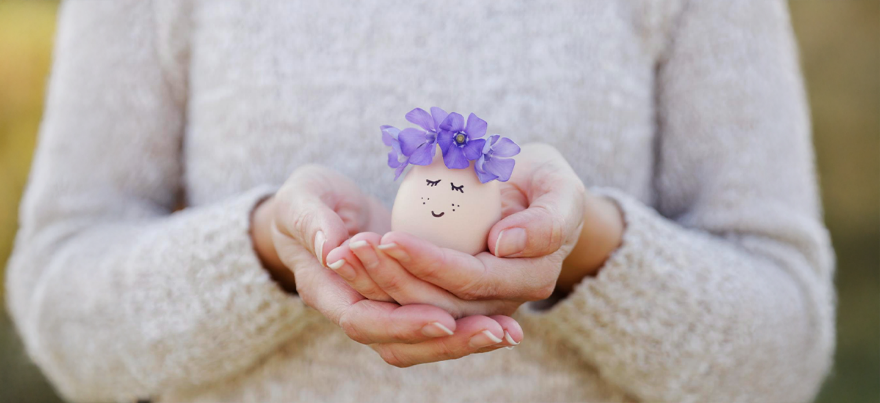 Woman holding an egg with a flower crown, symbolizing egg donation and fertility care – BirthRight by Rainbow Hospitals